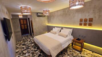 Een moderne slaapkamer met een groot bed, een nachtkastje, een aan de muur bevestigde televisie en een bijzondere plafondlamp.