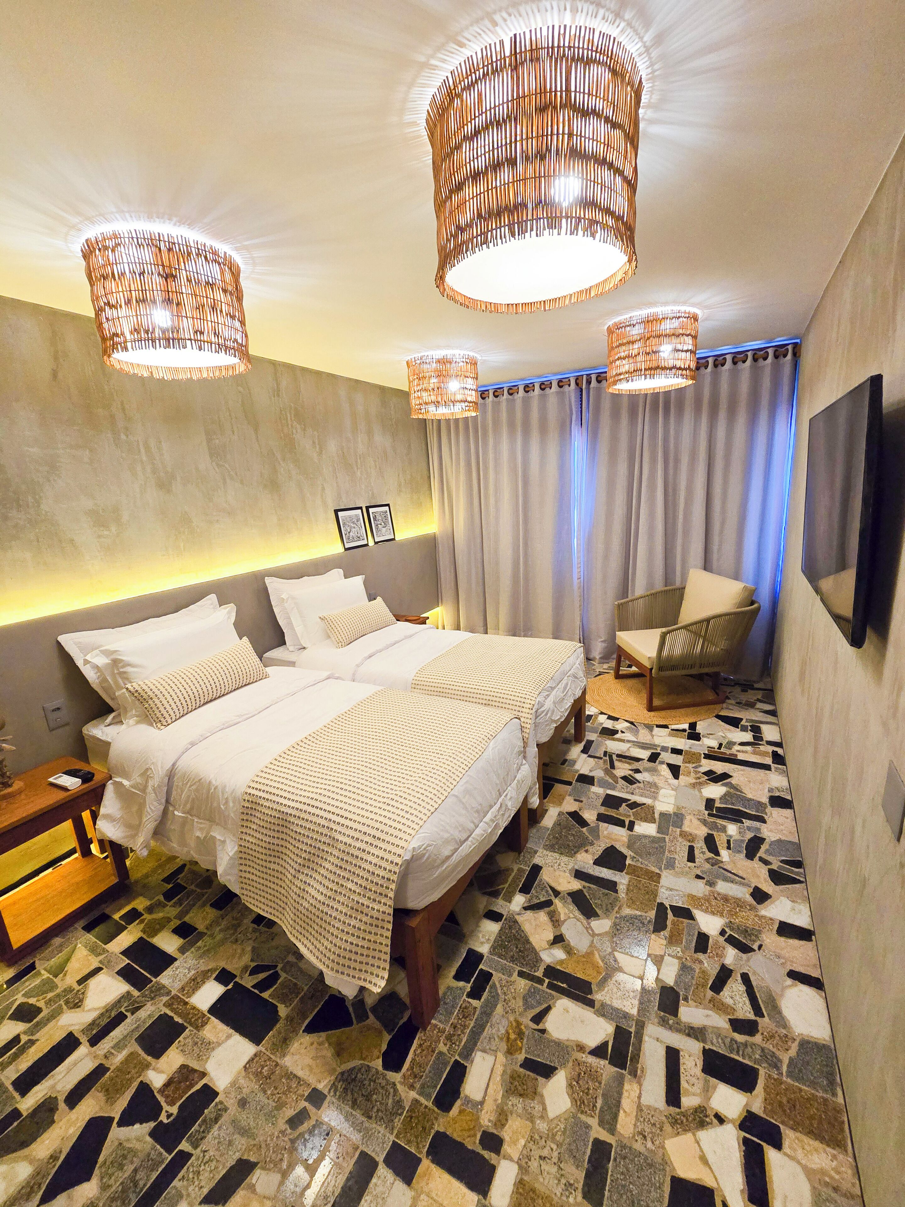 Een moderne slaapkamer met een groot bed, twee nachtkastjes, een stoel, een televisie en een vloer met een patroon.