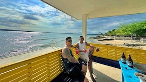 A covered outdoor seating area with a view of the sea and a sandy beach. - Arenzo Beach Resort Calatagan Batangas (Calatagan)