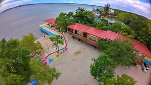 A coastal property with a swimming pool, a red-roofed building, and a parking area. - Arenzo Beach Resort Calatagan Batangas (Calatagan)