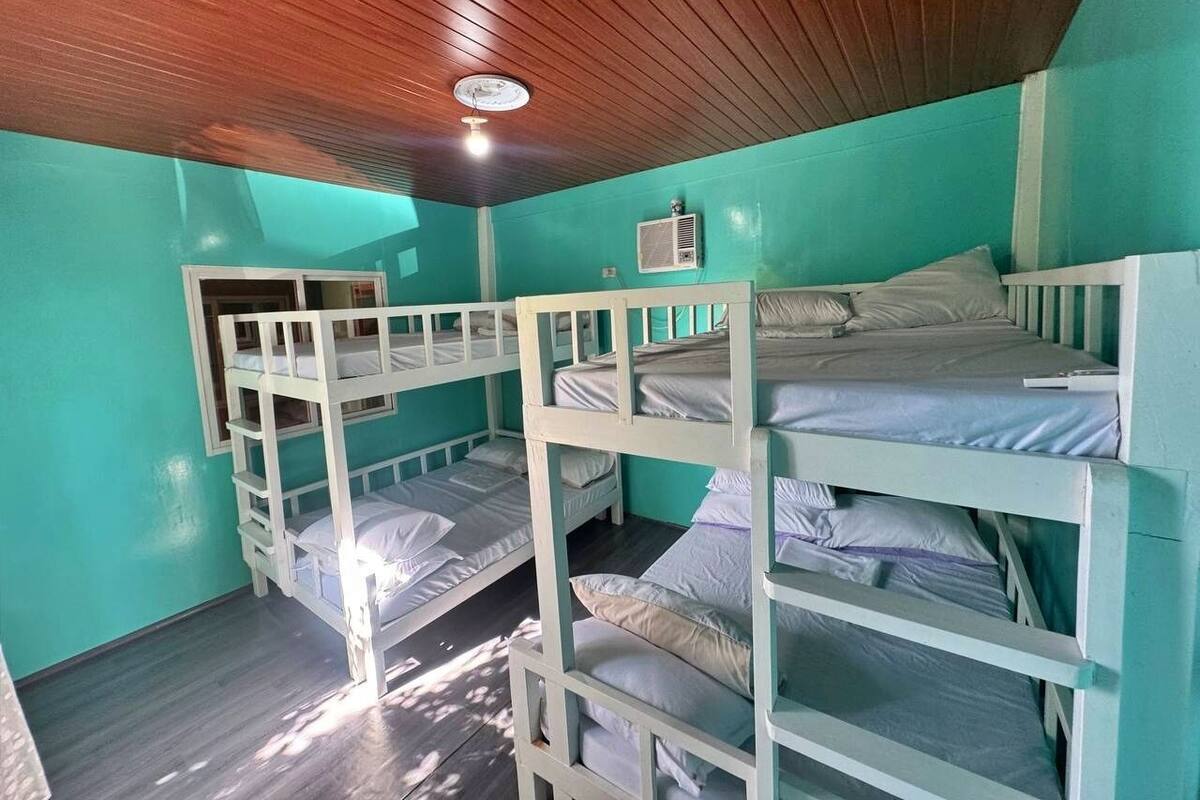 Ein Schlafraum mit drei Etagenbetten, einem Deckenventilator und einer Klimaanlage.