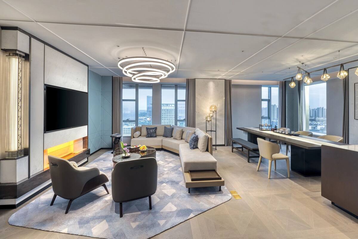 Un salon moderne avec un canapé, des fauteuils, un téléviseur et une cheminée.