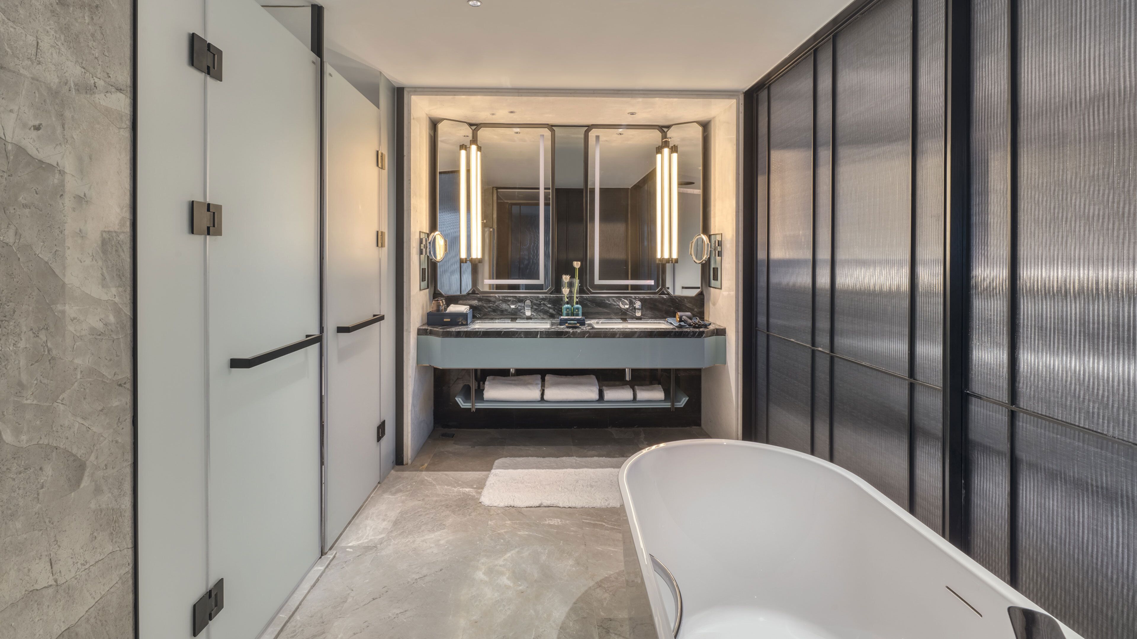 A modern bathroom with a large mirror, two sinks, and a bathtub.