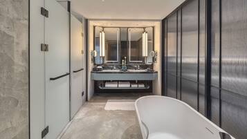 A modern bathroom with a large mirror, two sinks, and a bathtub.