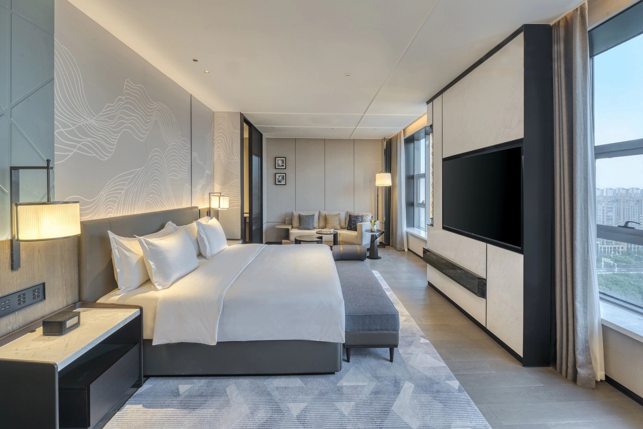 Una habitación de hotel moderna con una cama grande, un televisor, un sofá y un escritorio.