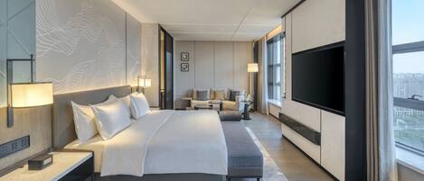 Una habitación de hotel moderna con una cama grande, un televisor, un sofá y un escritorio.
