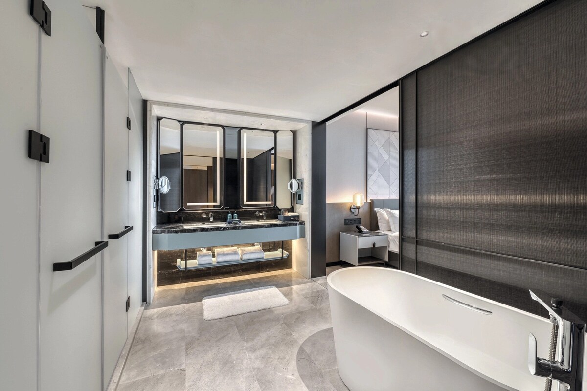 A modern bathroom with a freestanding bathtub, a large mirror, and a vanity with a double sink.