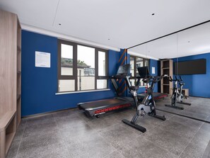 Ein Fitnessraum mit Trainingsgeräten, einem großen Fenster und einer blauen Wand.