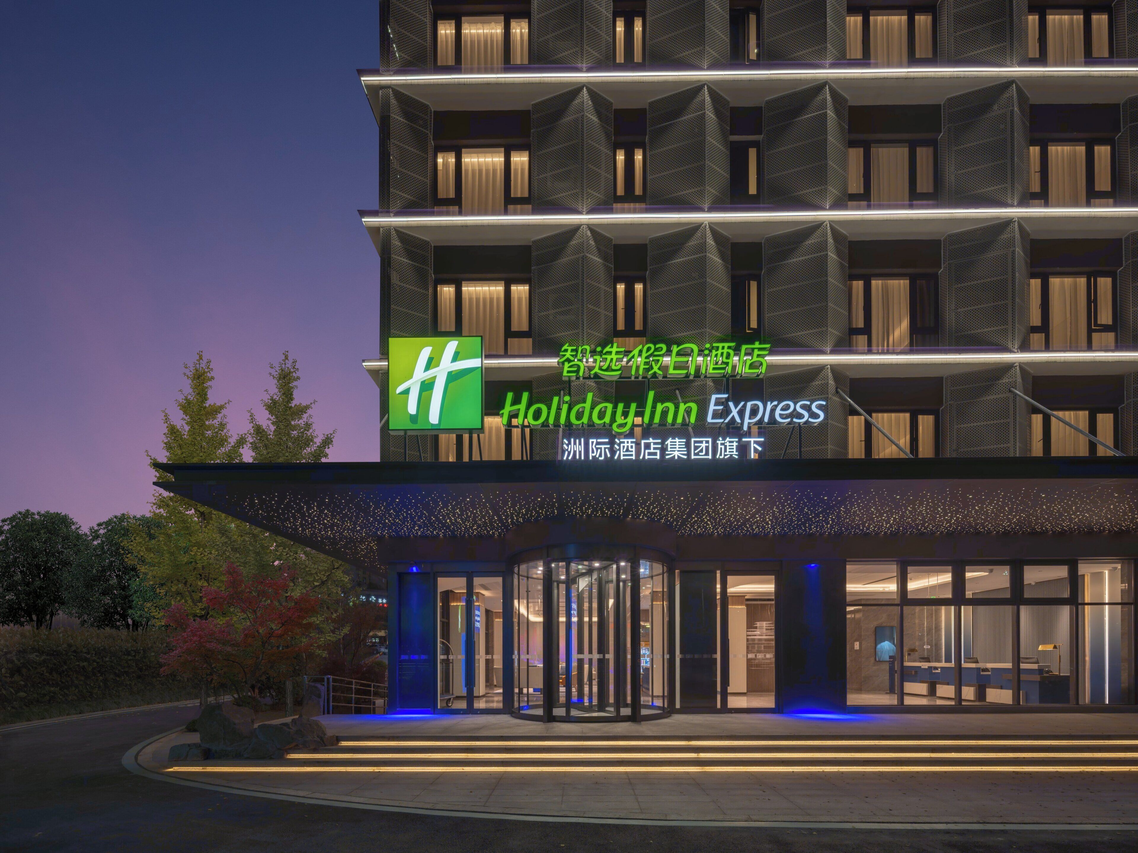 A Holiday Inn Express hotel with a modern facade, large glass entrance, and a prominent green logo.