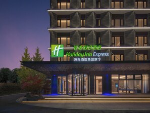 Ein Holiday Inn Express Hotel mit moderner Fassade, großem Glaseingang und einem markanten, grünen Logo.