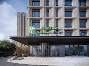 A Holiday Inn Express hotel with a modern facade, large windows, and a prominent entrance with glass doors. - Holiday Inn Express Chongqing Ciqikou Ancient Town by IHG (Chongqing)