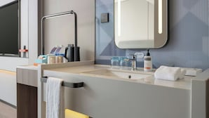 Un baño moderno con un espejo grande, un perchero para toallas, un lavamanos y una cafetera.