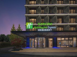 Un hotel Holiday Inn Express con fachada moderna, ventanas amplias y una entrada destacada.