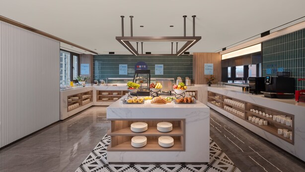 Cocina de hotel moderna con una isla central, diversos alimentos y una cafetera.