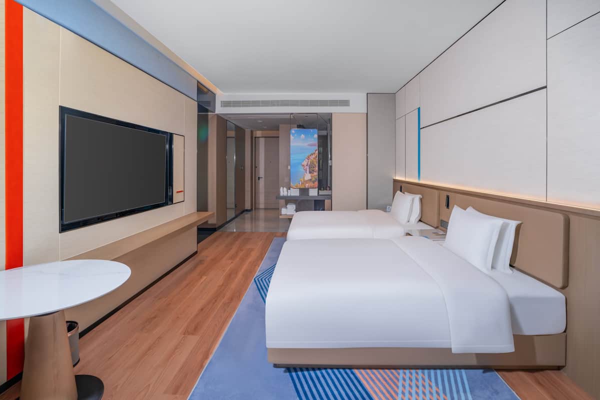 Habitación de hotel con una cama grande, televisión, una mesita y vistas a un paisaje costero.