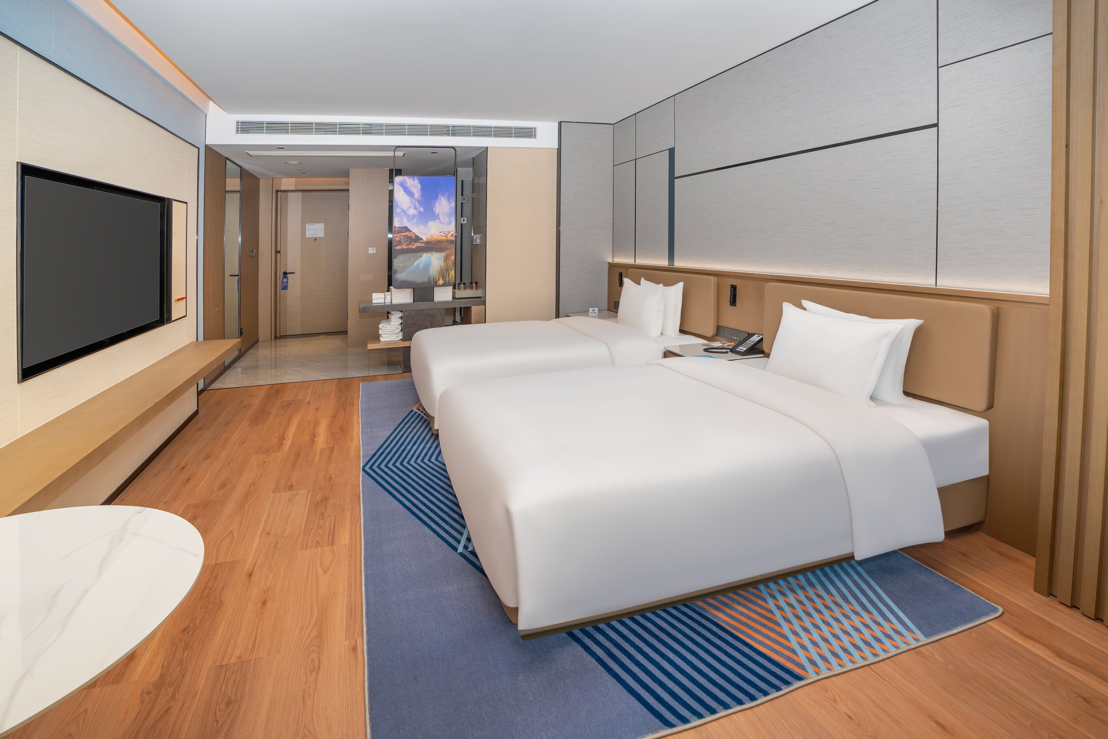 A hotel room with a large bed, a TV, a desk, and a bathroom visible through an open door.