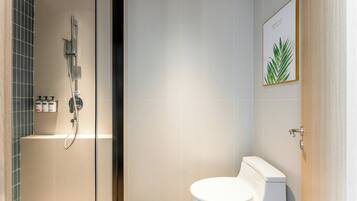 A modern bathroom with a shower, toilet, and a framed picture on the wall.