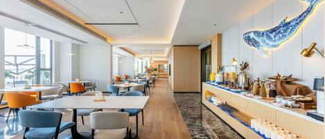 A modern hotel lobby with a long reception desk, seating area, and a large wall mural.