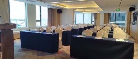 A conference room with multiple tables, chairs, and a podium.