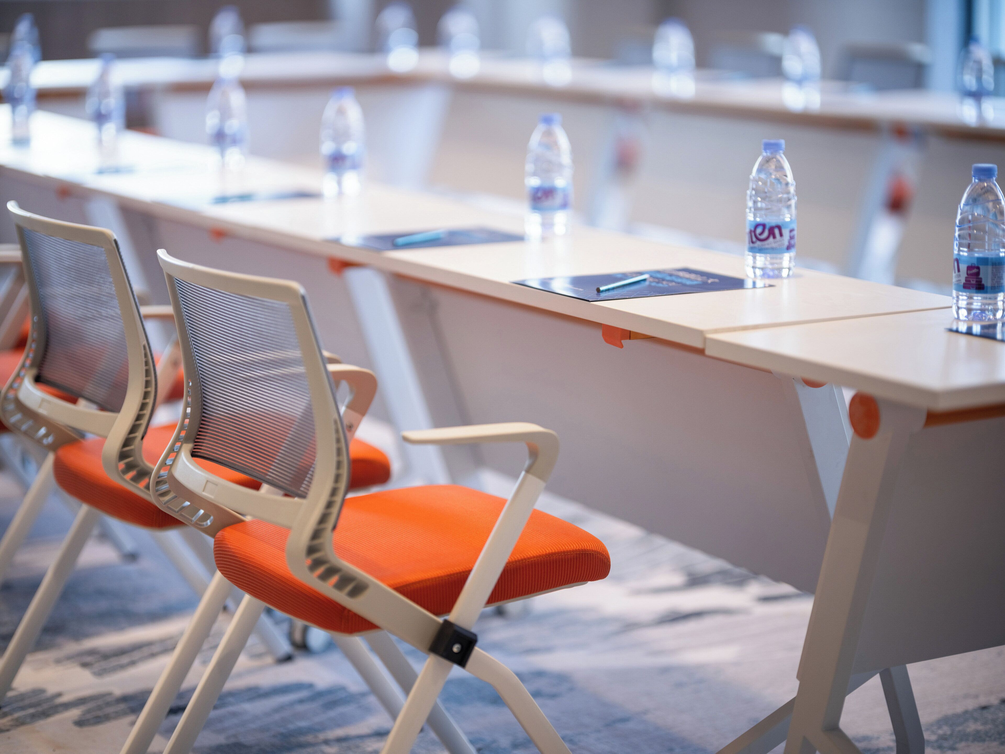 A conference room with a long table, chairs, and water bottles.