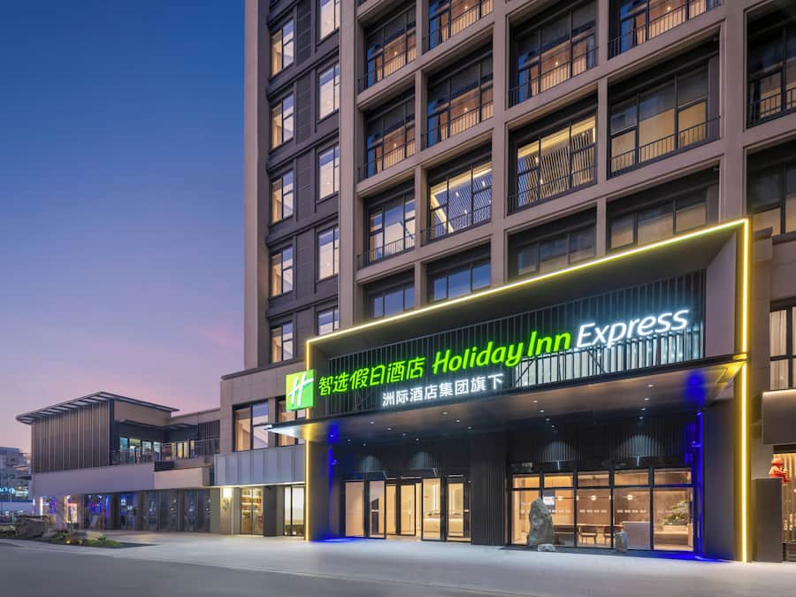 Edificio de Holiday Inn Express con fachada moderna, grandes ventanales y una entrada destacada.