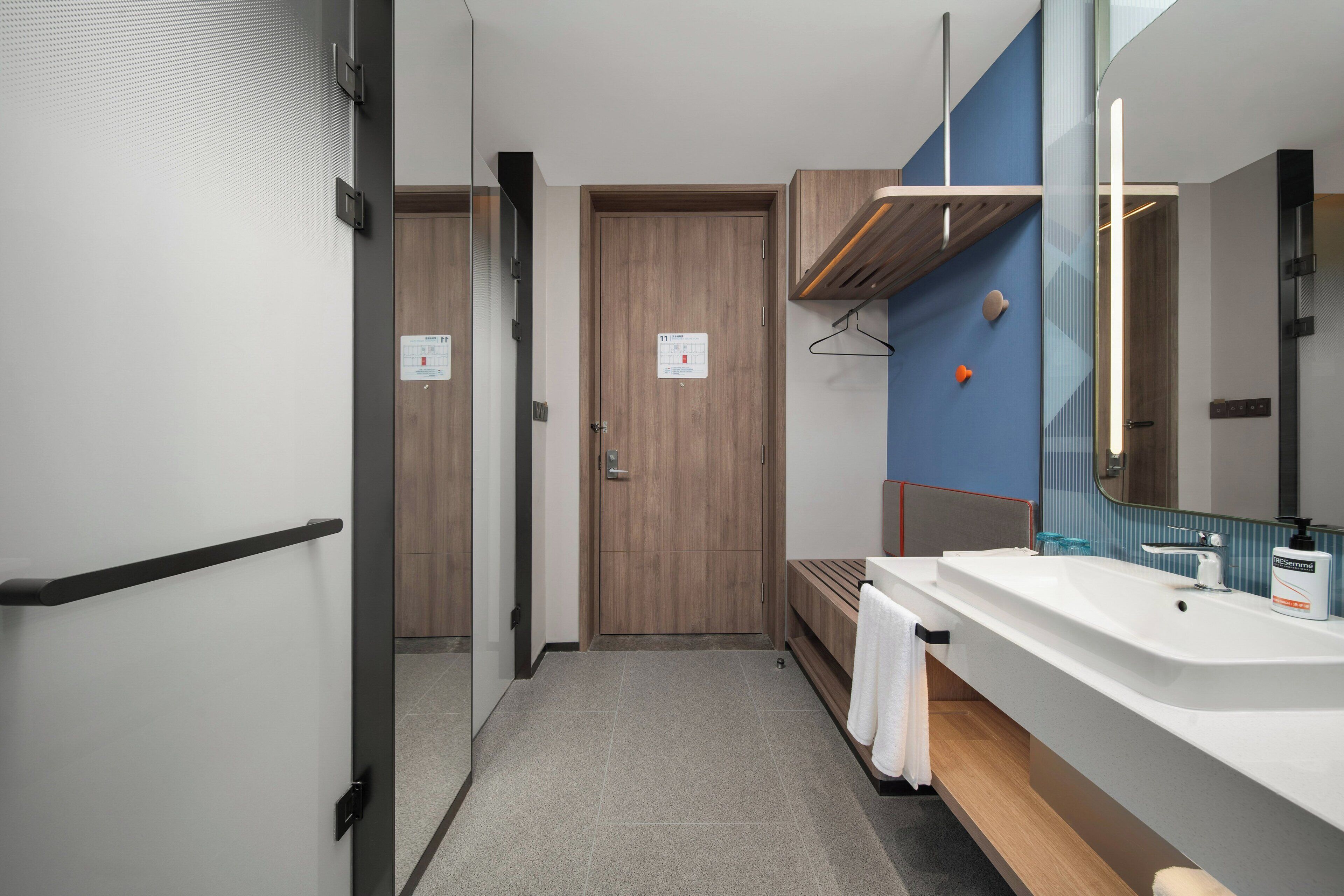 Un baño moderno con un espejo grande, un lavamanos y una puerta de madera.