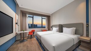 Et hotelværelse med en stor seng, et skrivebord, en stol og et fjernsyn.