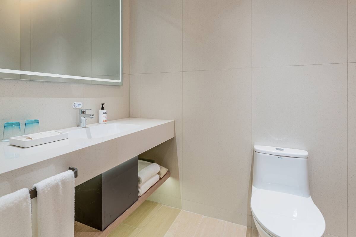 Een moderne badkamer met een witte wastafel, spiegel en toilet.