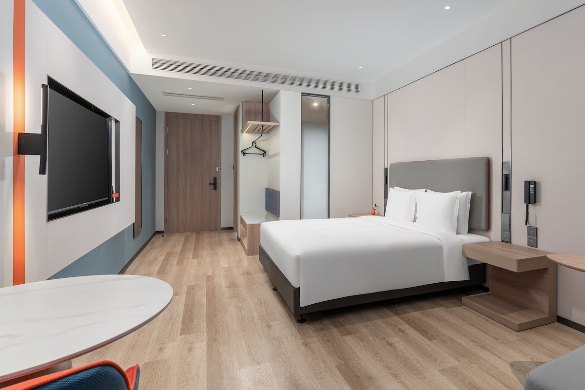 Una habitación de hotel moderna con cama, mesita de noche y escritorio con silla.
