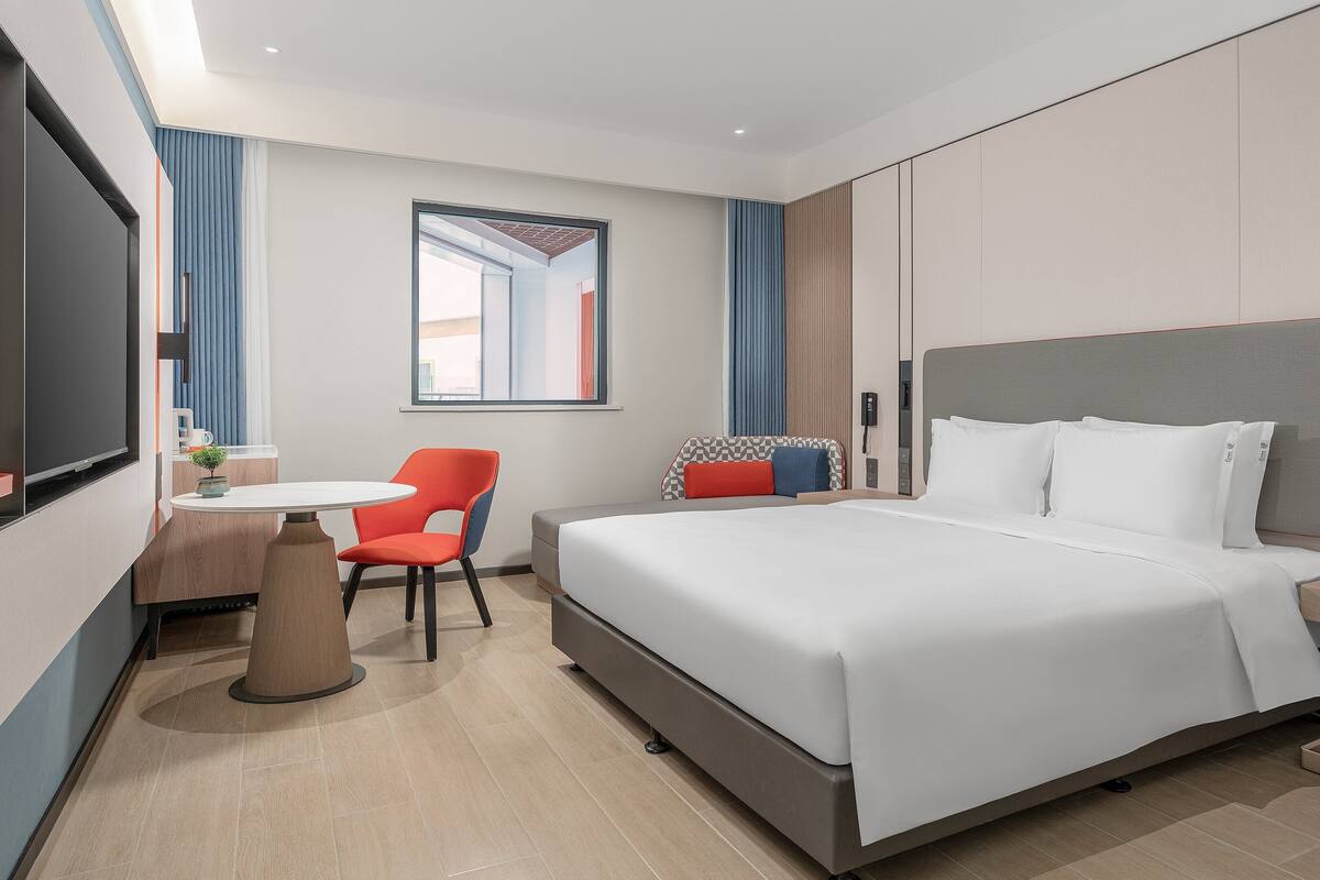 Een hotelkamer met een bed, bureau, stoel en televisie.