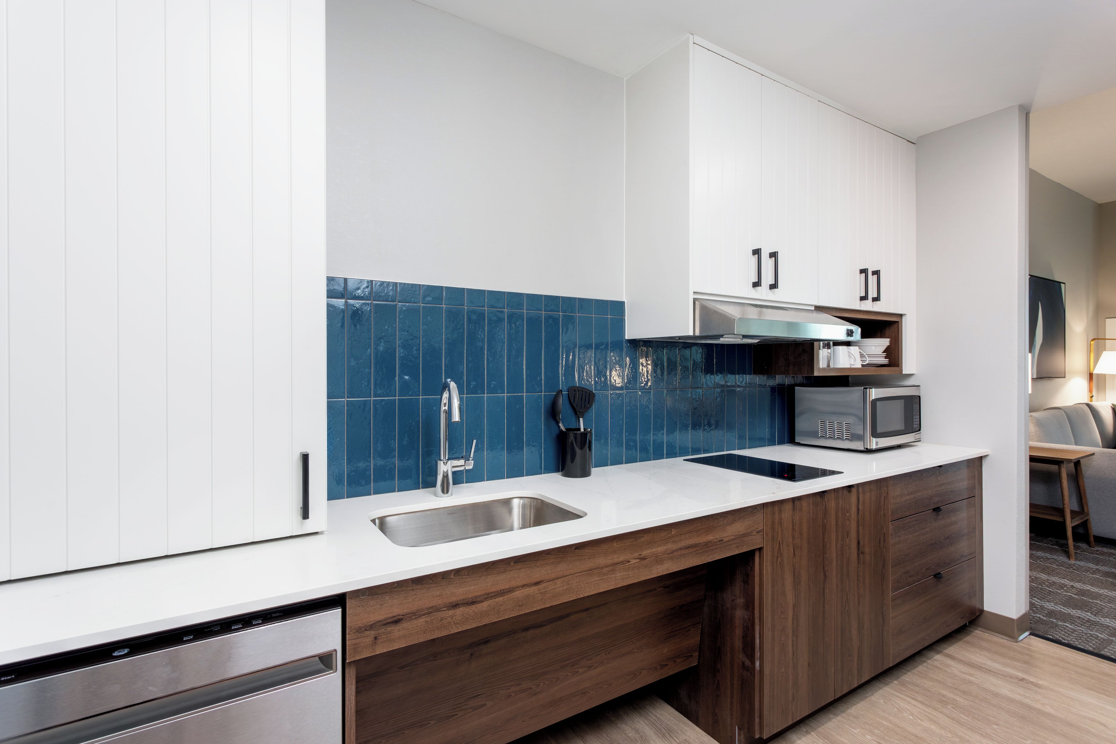 A modern kitchen with white cabinets, a stainless steel sink, and a microwave.