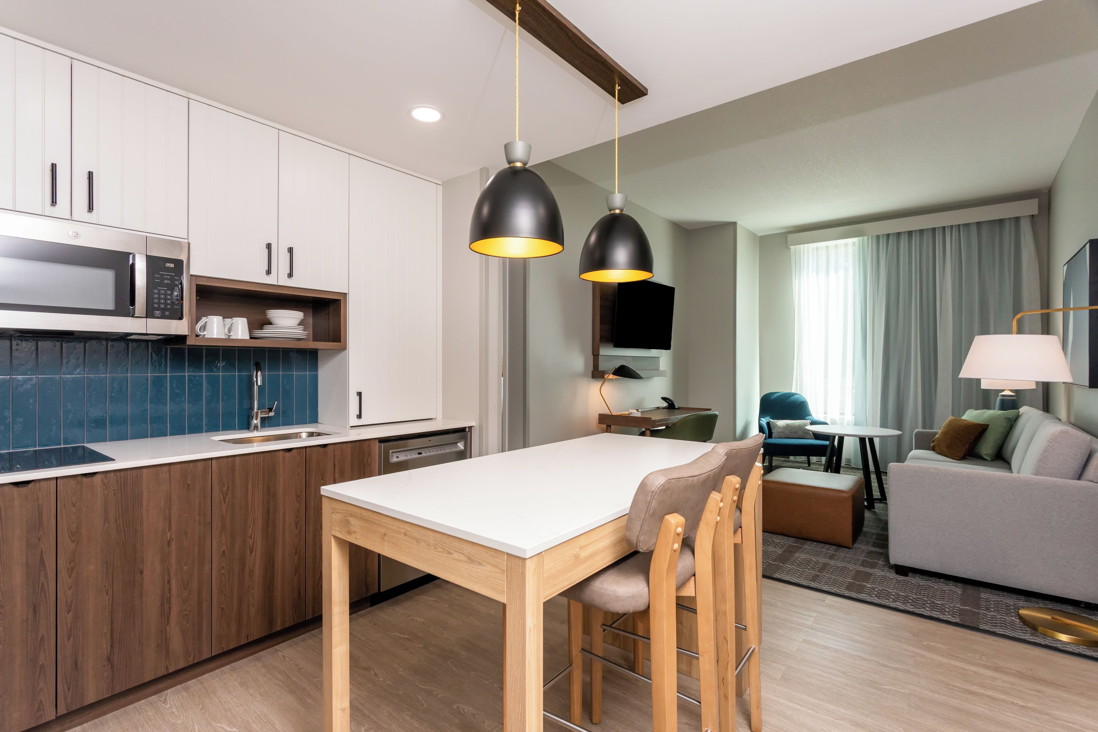 A modern kitchen with wooden cabinets, a microwave, and a dining area with a table and chairs.