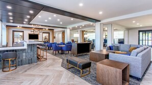 Un hall d’hôtel moderne avec un bar, des sièges et un grand canapé.