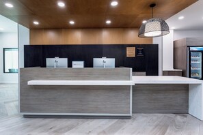 Una reception dal design moderno, con un pannello in legno sullo sfondo e un bancone bianco.