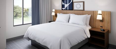 A hotel room with a large bed, two bedside lamps, a nightstand, and a window with a view of trees.