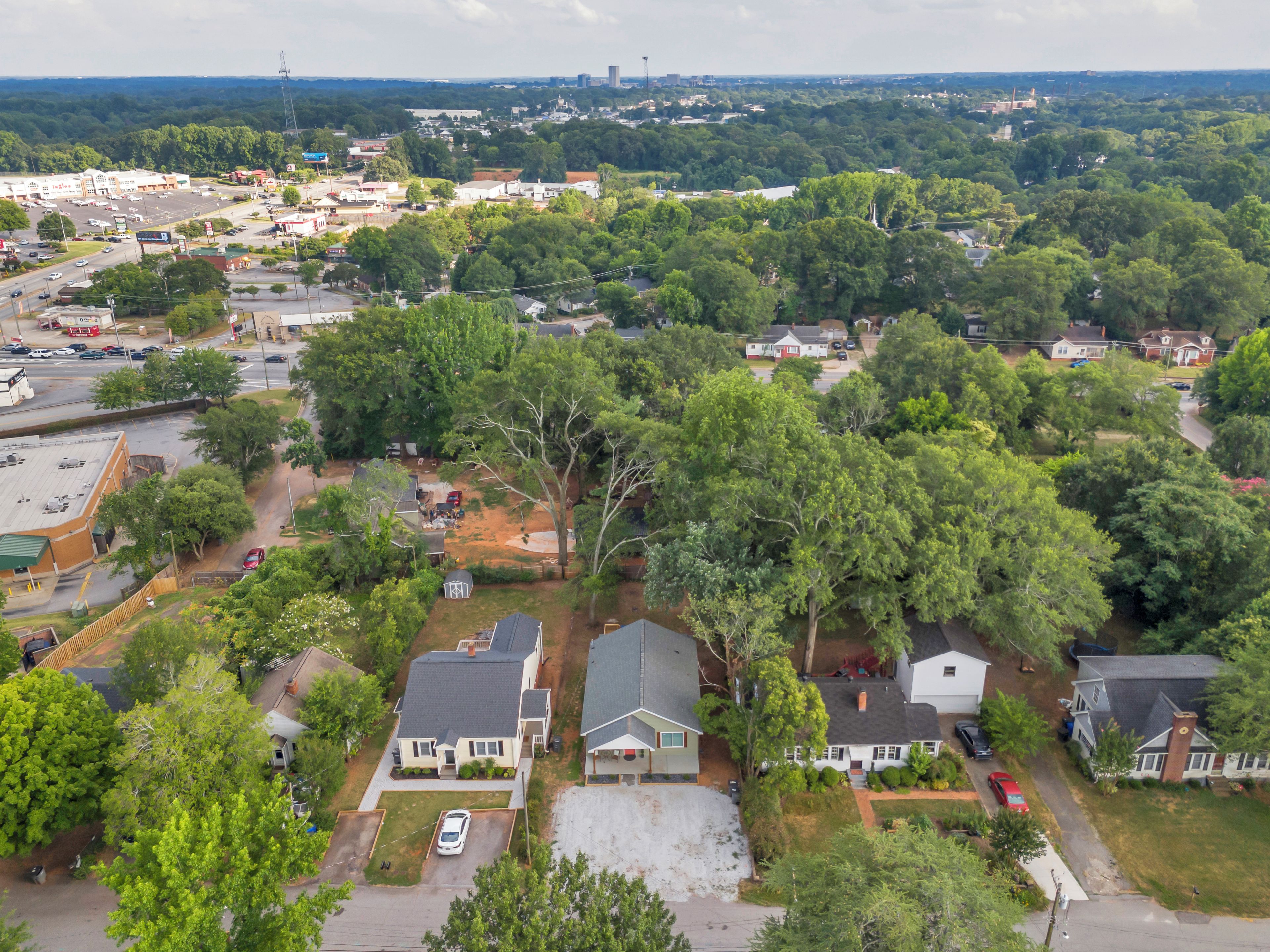 An aerial view of a residential area with houses, roads, and a large commercial area in the background.