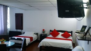 Une chambre d’hôtel avec deux lits simples, un canapé, une télévision et une petite table avec une chaise.