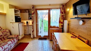 A compact living space with a kitchenette, a dining area, and a TV mounted on the wall. - 200m from ski slopes, 1st floor, balcony, tv, 26m², Montalbert (La Plagne)