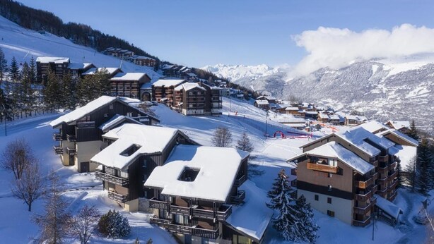 A snow-covered mountain resort with chalet-style buildings, ski slopes, and a clear view of the surrounding mountains. - 200m from ski slopes, 1st floor, balcony, tv, 26m², Montalbert (La Plagne)