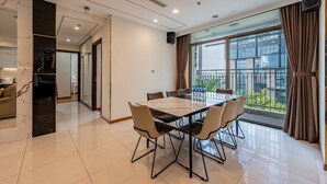 A modern dining area with a large table and chairs, a marble column, and a view of the city through large windows. - 4 Bedroom Apartment for Rent at Vinhomes Central Park (Binh Thanh District)