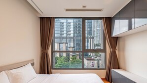 A modern hotel room with a large window, a bed, and a built-in wardrobe. - 4 Bedroom Apartment for Rent at Vinhomes Central Park (Binh Thanh District)