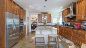 Una cocina moderna con armarios de madera, electrodomésticos de acero inoxidable y una isla central con taburetes.