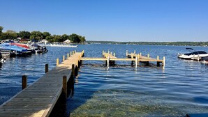 A wooden dock extending into calm water with boats docked at the end. - Lakefront Views + Walk to Dining | Kayaks + Firepit (Pewaukee)