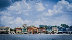 A waterfront with colorful buildings, a clear sky, and calm water. - Lakefront Views + Walk to Dining | Kayaks + Firepit (Pewaukee)