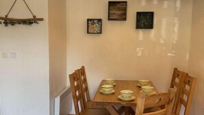 Een eetruimte met een houten tafel en stoelen, een hanglamp en wanddecoratie.
