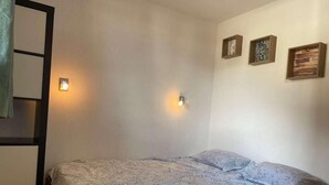 Een slaapkamer met een bed, twee wandlampen en drie ingelijste foto's aan de muur.