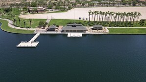 An aerial view of a resort with a dock, swimming pool, and a desert landscape in the background. - Estrella Skies Backyard Delight, Stunning Pool 4 Beds 2 Bath, Vacation Retreat (Goodyear)