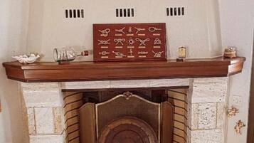 A fireplace with a framed collection of nautical knots and a ship model.