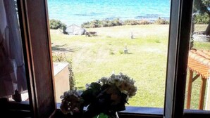 Blick aus dem Fenster auf eine grüne Wiese mit blauem Meer im Hintergrund.