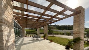 A covered patio area with stone walls, a pergola structure, and outdoor seating. - Holiday Inn Express & Suites St. Vincent - Grenadines by IHG (Diamond)